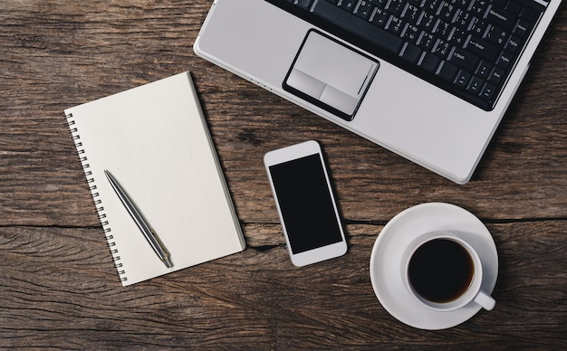 cosas de oficina de mesa de madera con Bloc de notas, computadora portátil y taza de café, Bloc de notas, pluma, teléfono inteligente