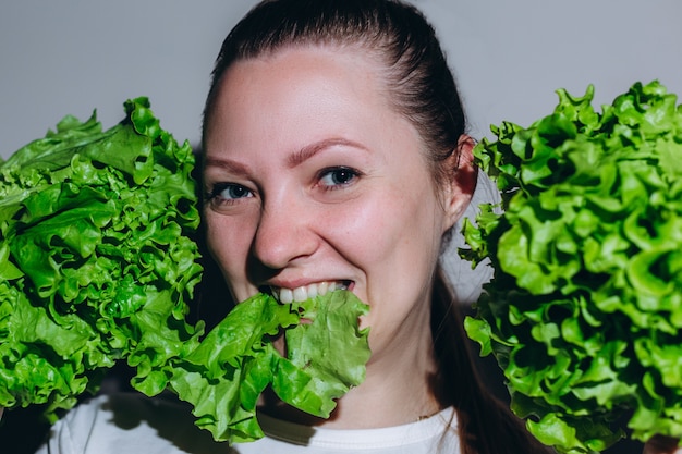 Cosecha de cerca de mujer sonriente masticando ensalada verde. Concepto de nutrición y estilo de vida saludable