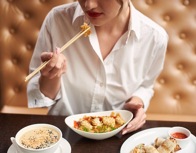 Cosecha de mujer en blanco pedir comida en restaurante japonés.