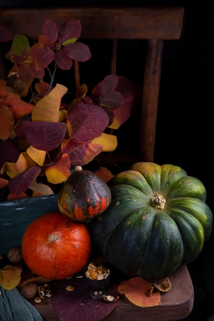 Cosecha otoñal de calabazas en una mesa de madera oscura con hojas de otoño
