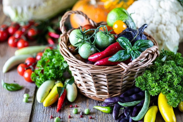 Cosecha otoñal de verduras en una cesta de mimbre: tomates, frijoles, calabaza, calabaza, repollo, verduras, perejil.