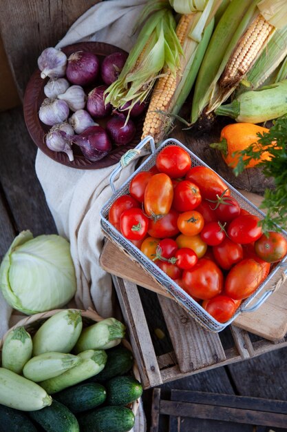 Foto cosecha de tomates en una cesta en la vista superior de la mesa variedad de verduras de verano sobre un fondo de madera pepinos de repollo tomate de diferentes variedades