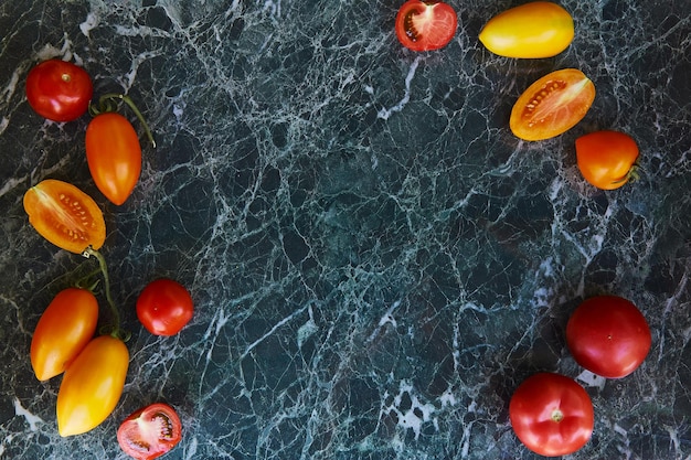 Cosecha de tomates rojos, naranjas y amarillos brillantes sobre fondo de mármol verde Comida natural cultivada en casa Espacio de copia Comida de vista superior