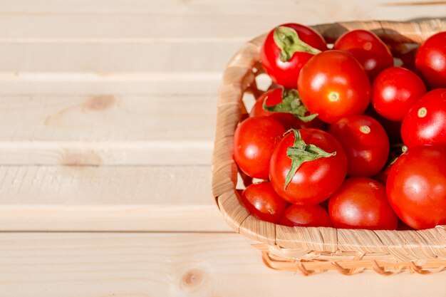 cosechar tomates en la cesta de mimbre en la mesa de madera