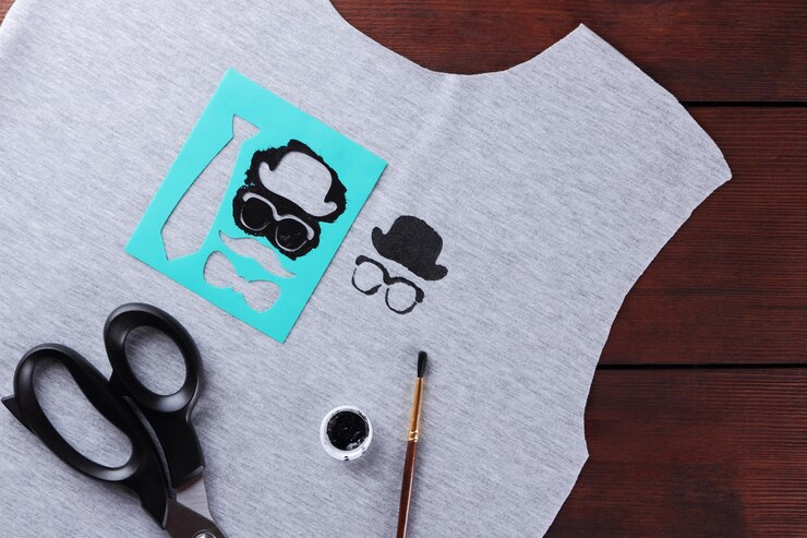 Foto coser camisetas para niños con dibujos hechos a mano tela gris en tablas de madera proceso de confección