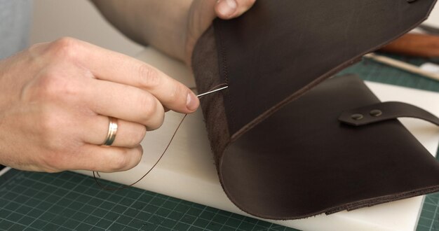 Coser a mano un producto de cuero con aguja y hilo