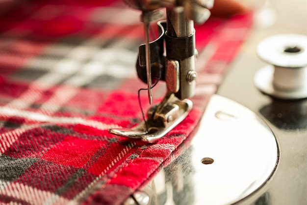 Coser tela en un primer plano de una máquina de coser Una mujer trabaja en una máquina de coser eléctrica en casa