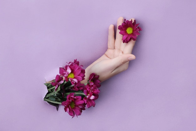 Cosmética natural para la piel de las manos, hidratación y nutrición. Extracto de flores, una mujer con pétalos rojos y flores en sus manos