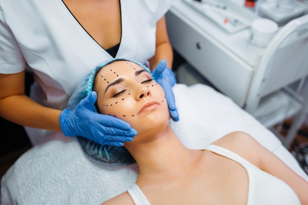 Cosmetician faz a injeção de botox em linhas pontilhadas no rosto do paciente feminino, preparação para injeções de botox. Procedimento de rejuvenescimento em salão de esteticista. Cirurgia cosmética contra rugas e envelhecimento