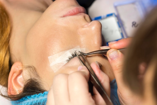 Cosmeticista com aplicação de cílios falsos ao cliente