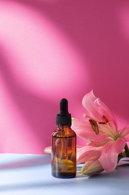 Cosmético da natureza em frasco de vidro com flor de lírio e sombra no fundo rosa Conceito de spa para cuidados com o rosto e corpo Soro de óleo de ácido hialurônico com produto de cuidados com a pele de colágeno e peptídeos