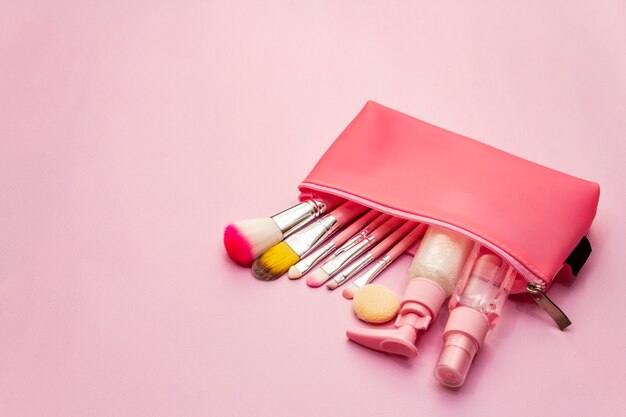 Cosmético maquiagem definido na bolsa em fundo rosa
