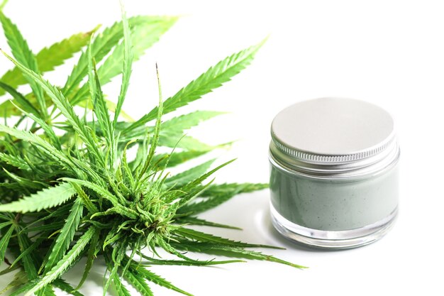 Cosméticos CBD. Planta e frasco de cannabis verde com um creme hidratante de rejuvenescimento.