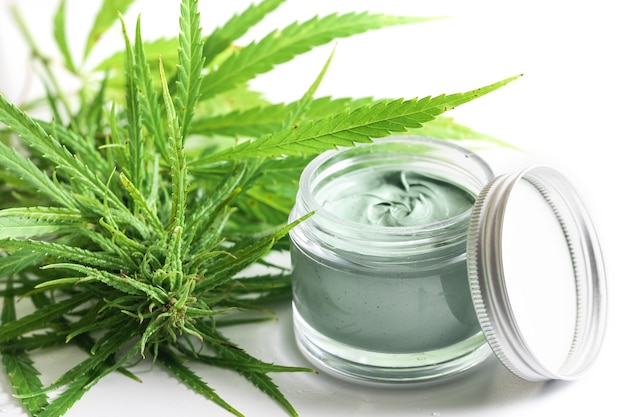 Cosméticos CBD. Planta e frasco de cannabis verde com um creme hidratante de rejuvenescimento.
