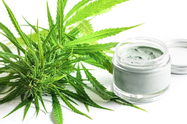 Cosméticos CBD. Planta e frasco de cannabis verde com um creme hidratante de rejuvenescimento.