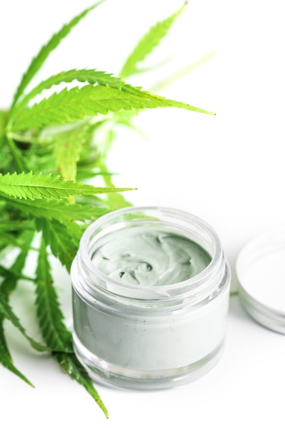 Cosméticos cbd. planta e frasco de cannabis verde com um creme hidratante de rejuvenescimento.