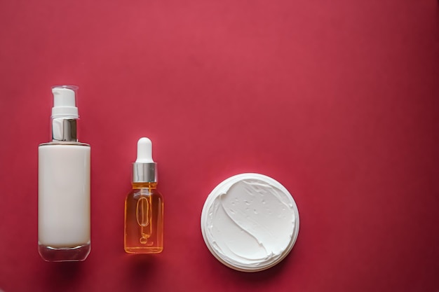 Cosméticos para el cuidado de la piel y productos de belleza antienvejecimiento botellas de lujo para el cuidado de la piel suero de aceite y crema facial sobre fondo de coral