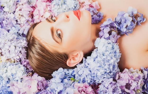 Cosméticos de maquiagem e beleza natural de cuidados com a pele mulher deitada em flores unidade com natureza flor menina wi