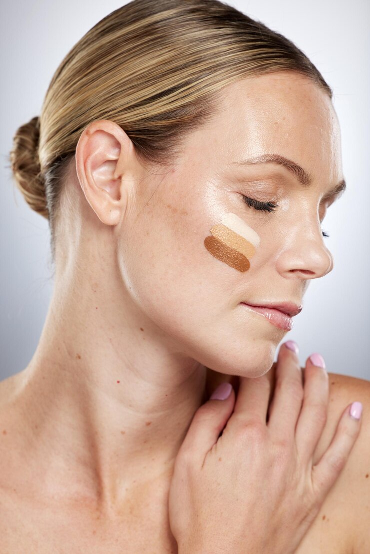 Foto cosméticos de sombra de maquiagem e rosto de uma mulher com creme facial de base e cuidados com a pele em um fundo de estúdio cinza loção creme bb e modelo cosmético com amostras de corretivo para verificar se há correspondência