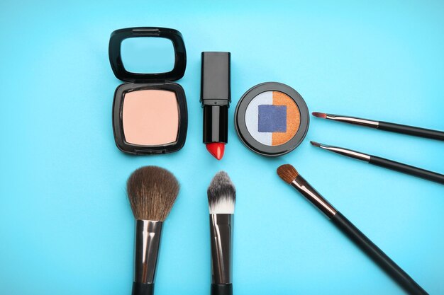 Cosméticos decorativos y herramientas de maquillador profesional sobre fondo de color
