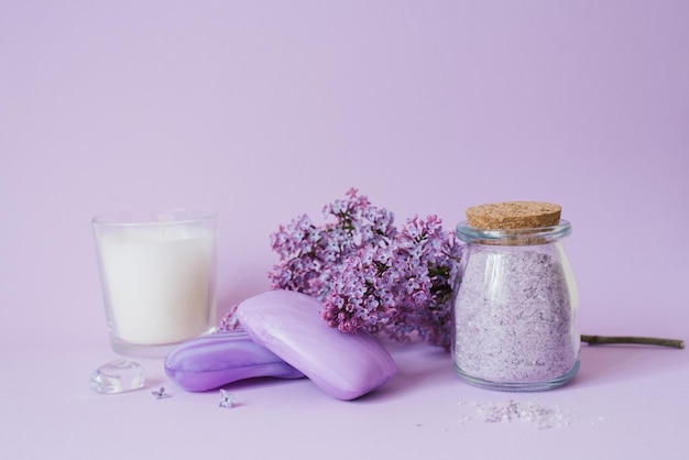 Cosméticos jabón y sales de baño y flores de lila en el fondo una capa uniforme