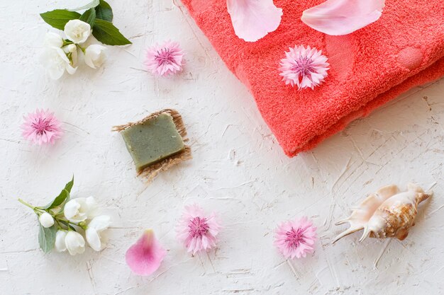 Cosméticos de mujer y toalla sobre un fondo blanco.