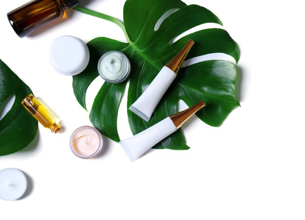 Cosméticos naturais e folhas em fundo branco