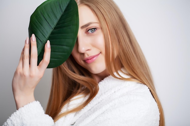 Cosméticos naturais, rosto de mulher bonita em folhas verdes.