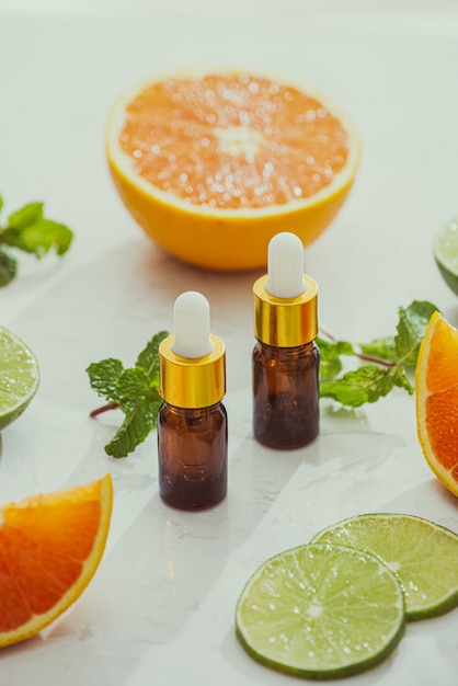 Cosméticos orgânicos com extratos de ervas de limão, laranja e hortelã em fundo brilhante