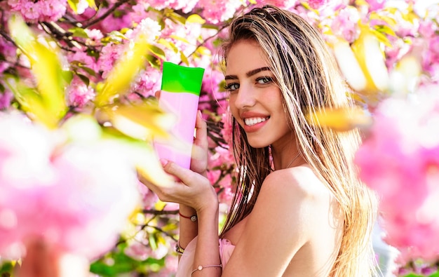 Foto cosméticos orgánicos de lujo mujer sonriente con botella de champú bálsamo o acondicionador herbal spa