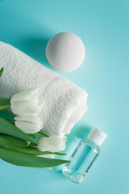Cosméticos orgânicos para tratamentos de spa e tulipas sobre fundo azul. Conceito de higiene e cuidados com a pele. Lugar para texto.