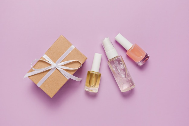 Cosméticos orgánicos y regalos para las fiestas. Endecha plana, vista superior botella de bomba de vidrio transparente, frasco de cepillo, frasco de suero hidratante sobre un fondo púrpura. SPA cosmética natural