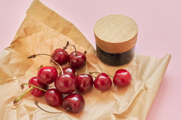 Cosméticos orgánicos saludables naturales, frutas, cerezas, botella con producto cosmético sobre fondo rosa. cosmetología, tratamiento, cuidado de la piel, terapia