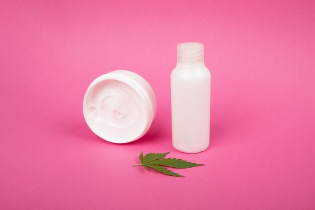 Cosméticos para cuidados com o corpo e anti-envelhecimento com extrato de maconha em um fundo rosa.