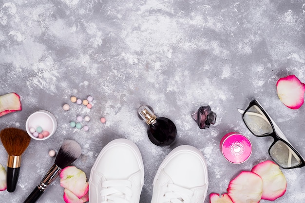 Cosméticos en perfumes y zapatos sobre un fondo gris con espacio de copia