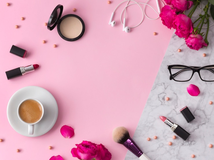 Foto cosméticos, pinceles de maquillaje, pintalabios, polvos y lentes con flores en el moderno mármol rosa.