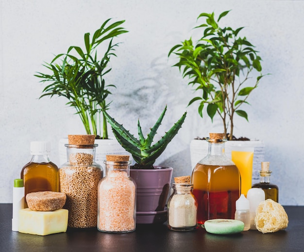 Cosméticos de spa caseros orgánicos y plantas caseras sobre la mesa en el baño. Botellas interiores vintage con champú y perlas de baño.