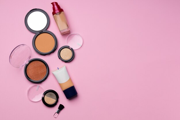 Cosméticos para la tez de la cara sobre fondo rosa de cerca