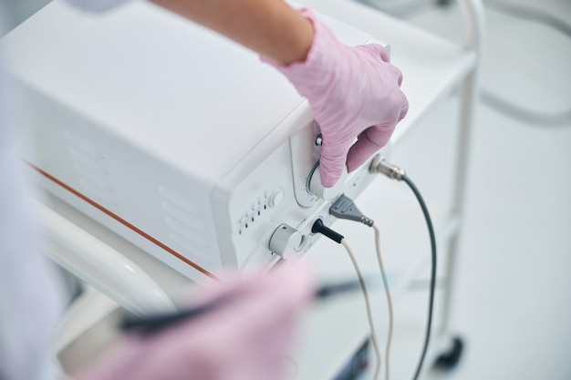 Foto una cosmetóloga caucásica experimentada que afina la máquina de electrocauterio antes de un procedimiento dermatológico