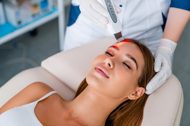 La cosmetóloga se hace la cara mientras se realiza el procedimiento de pelado facial por ultrasonido en el gabinete de cosmetología