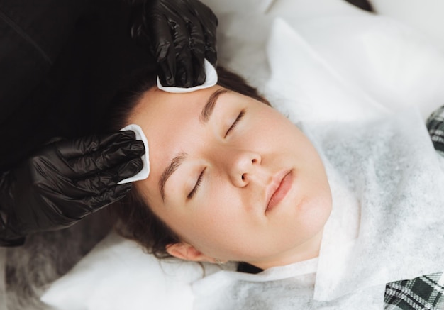 Una cosmetóloga hace un masaje facial cosmético para la cara relajada de una mujer joven en un spa de belleza Masaje para el cuidado facial concepto de cosmetología para el cuidado de la piel