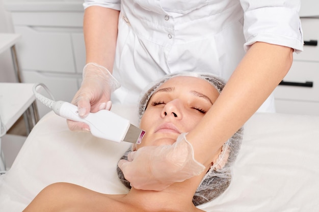 La cosmetóloga hace un peeling ultrasónico facial para el cuidado de la piel de la cara de una mujer rejuvenecedora en un salón de belleza