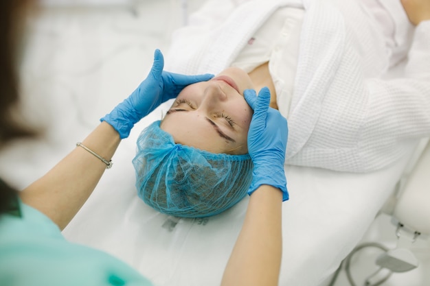 Cosmetóloga hacer masaje facial en salón de belleza