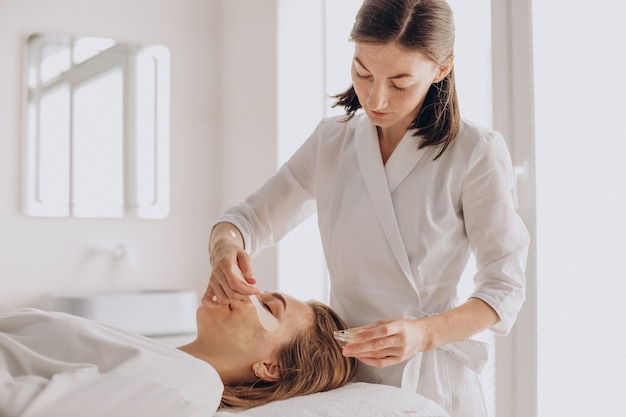 Cosmetóloga haciendo tratamiento facial y aplicando mascarilla