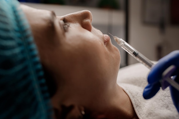 Una cosmetóloga inyecta una jeringa a un paciente