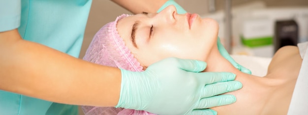 Cosmetóloga con manos enguantadas aplica una máscara hidratante con crema exfoliante en el rostro femenino Tratamiento de cosmetología facial Procedimientos para el cuidado facial