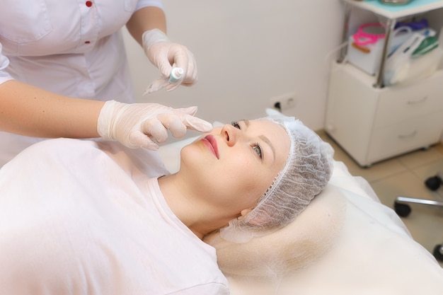 La cosmetóloga prepara los labios del cliente para el procedimiento de aumento.