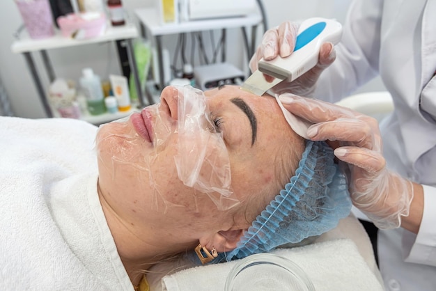 La cosmetóloga profesional con una máscara hace inyecciones de contorno facial a una paciente