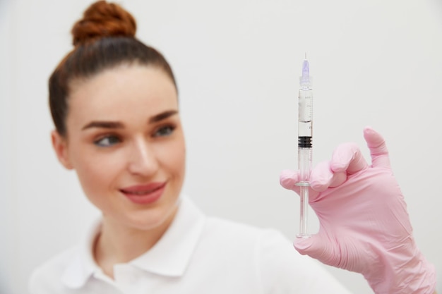 La cosmetóloga sostiene una jeringa para inyección con relleno hialurónico de colágeno para la cara o los labios