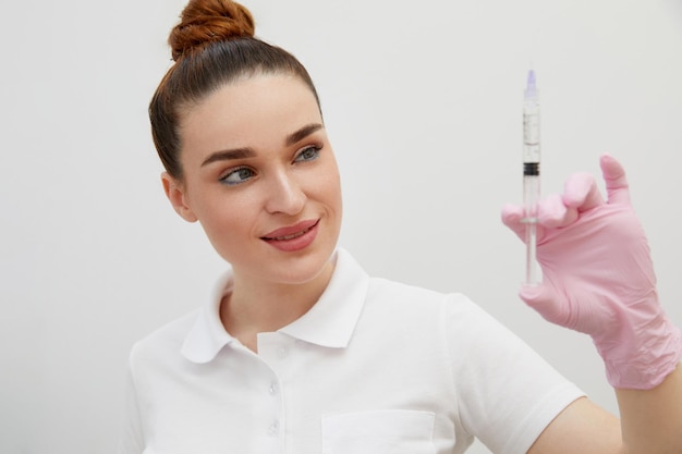 La cosmetóloga sostiene una jeringa para inyección con relleno hialurónico de colágeno para la cara o los labios
